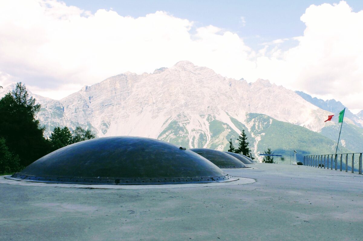 A summer view of the armored domes on the roof of the Forte di Oga above Bormio, with a rocky mountain behind (not a winter photo)