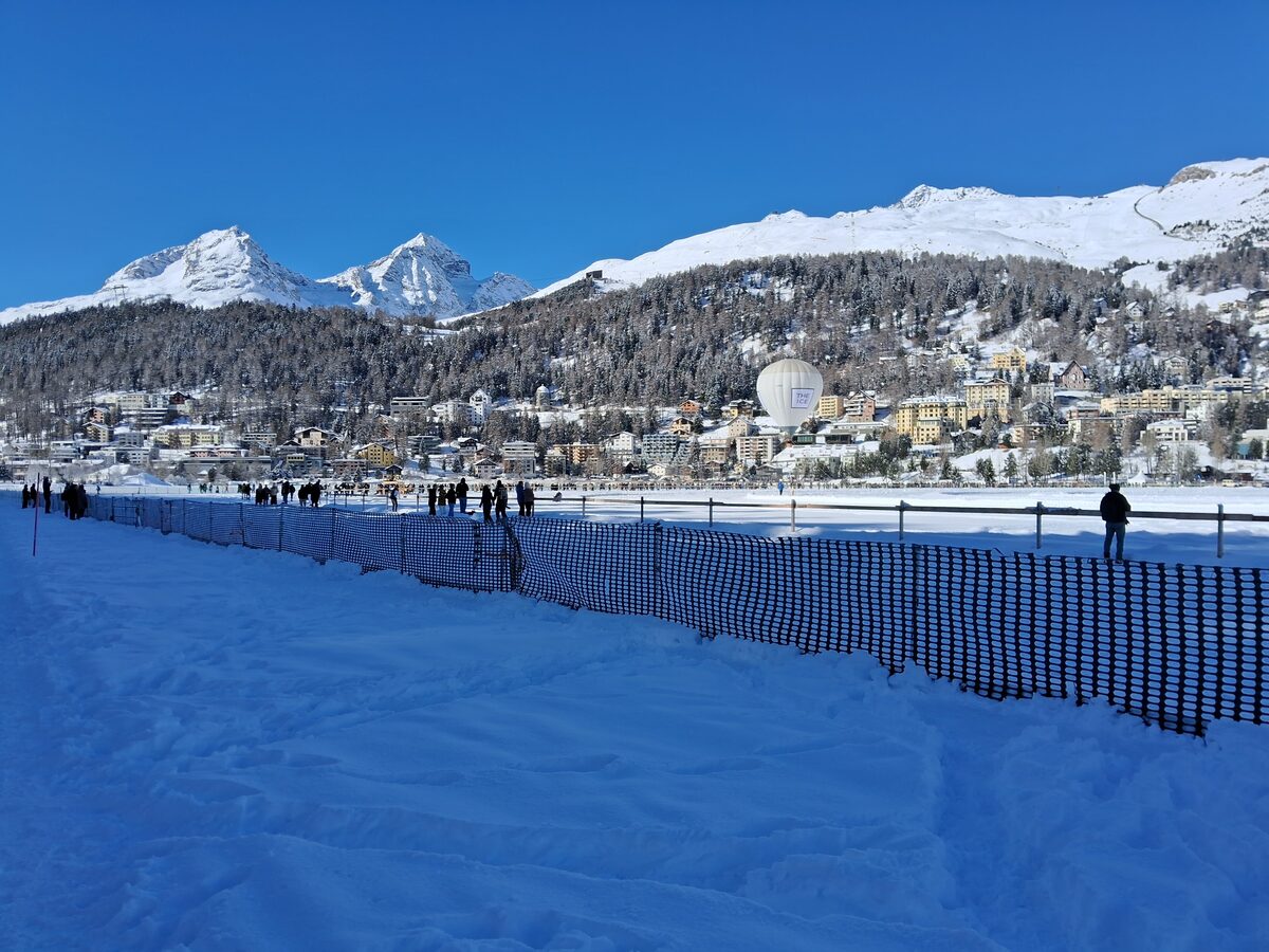 The frozen lake at St. Moritz in winter, with snow-covered mountains and the town across the lake