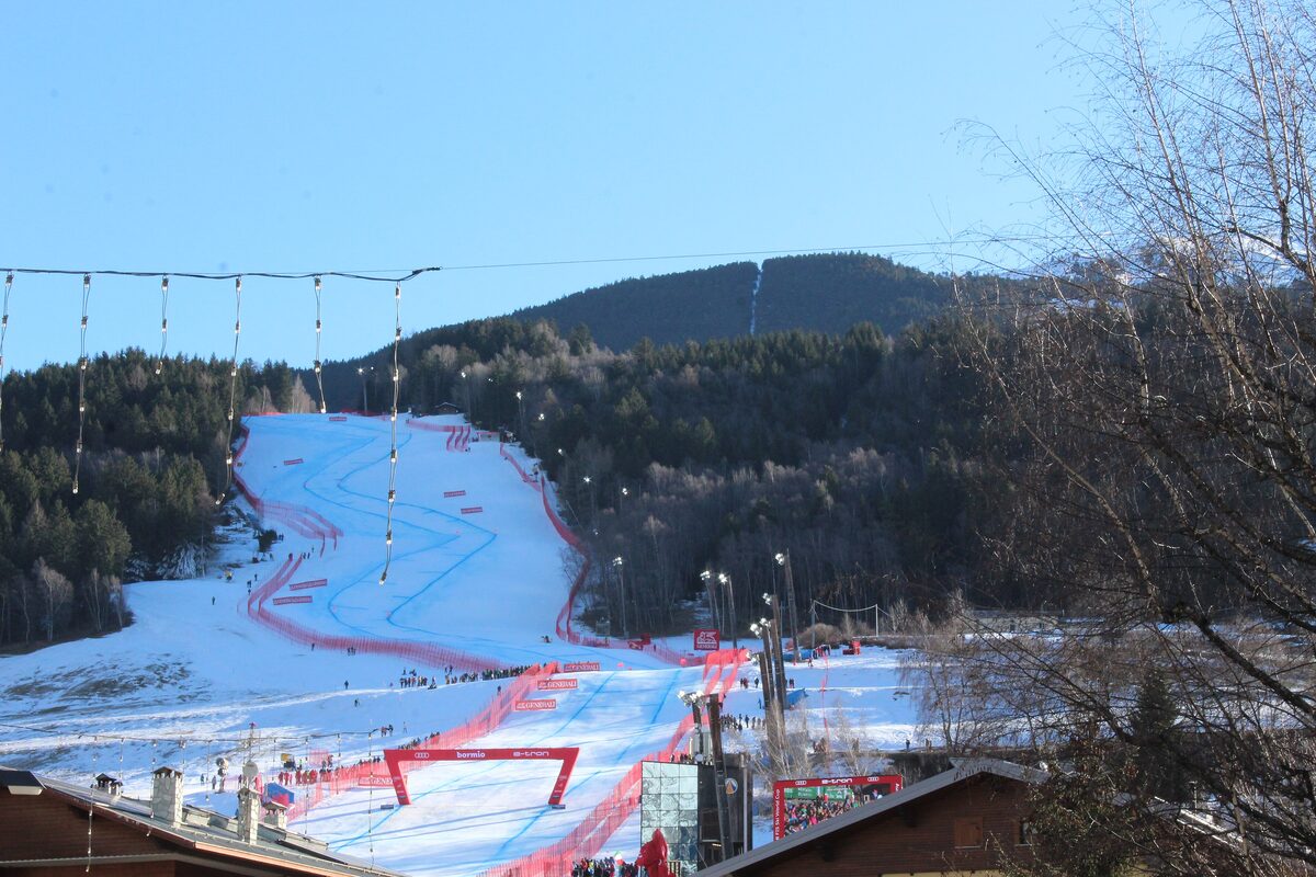 The red race course of the Stelvio piste above Bormio, with strings of lights hanging across the slope, a finish arch at the bottom and snow on the slope