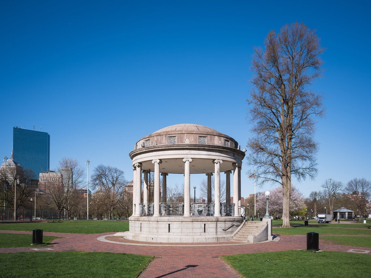The white Parkman Bandstand on Boston Common with towers behind