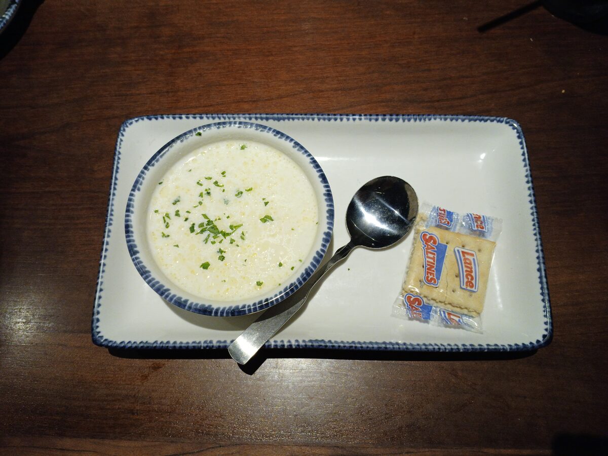 A bowl of creamy clam chowder served with oyster crackers