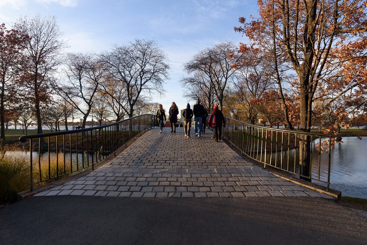 Walkers crossing a footbridge on the Charles River Esplanade in autumn