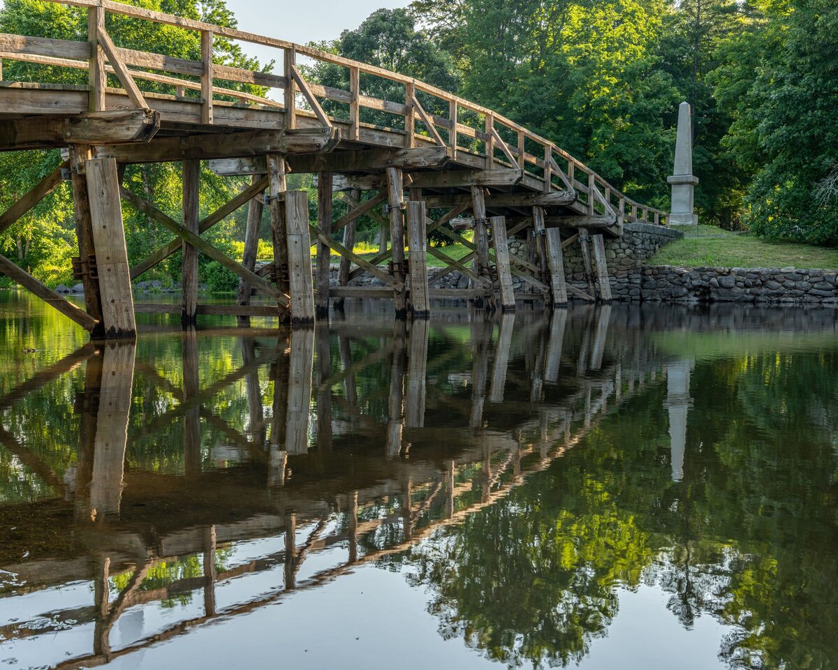 The wooden Old North Bridge reflected in the Concord River