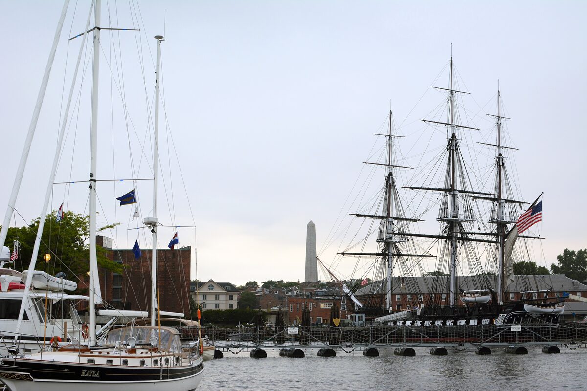 The three-masted USS Constitution at Charlestown Navy Yard with the monument behind
