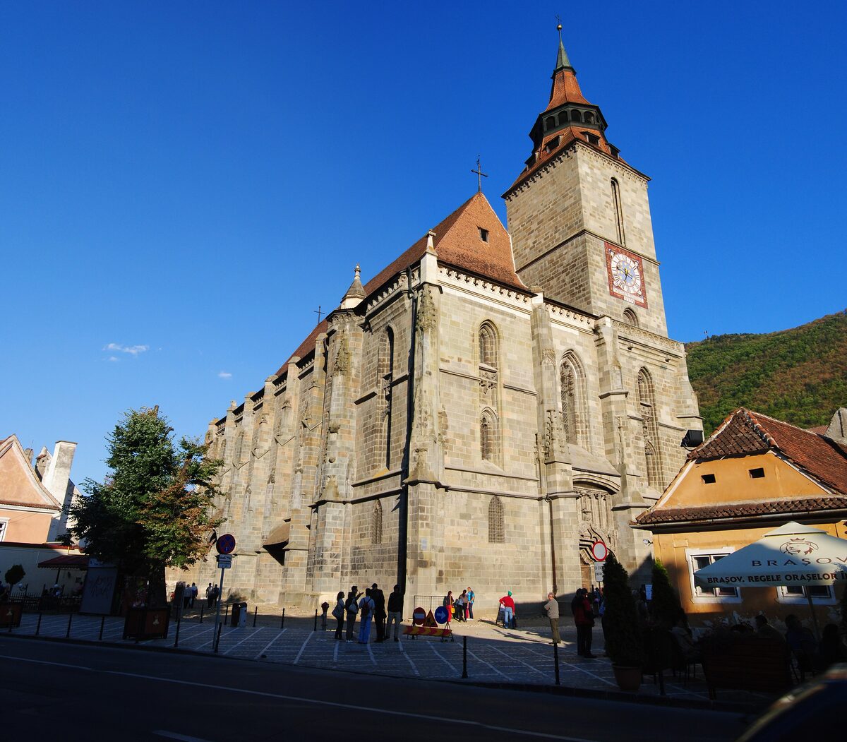 The Black Church in Brașov, a huge Gothic hall church of dark stone with a tall bell tower, against a deep blue sky