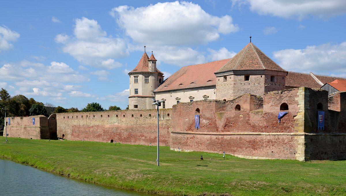 Făgăraș Citadel, a large castle with corner towers and red roofs behind a moat