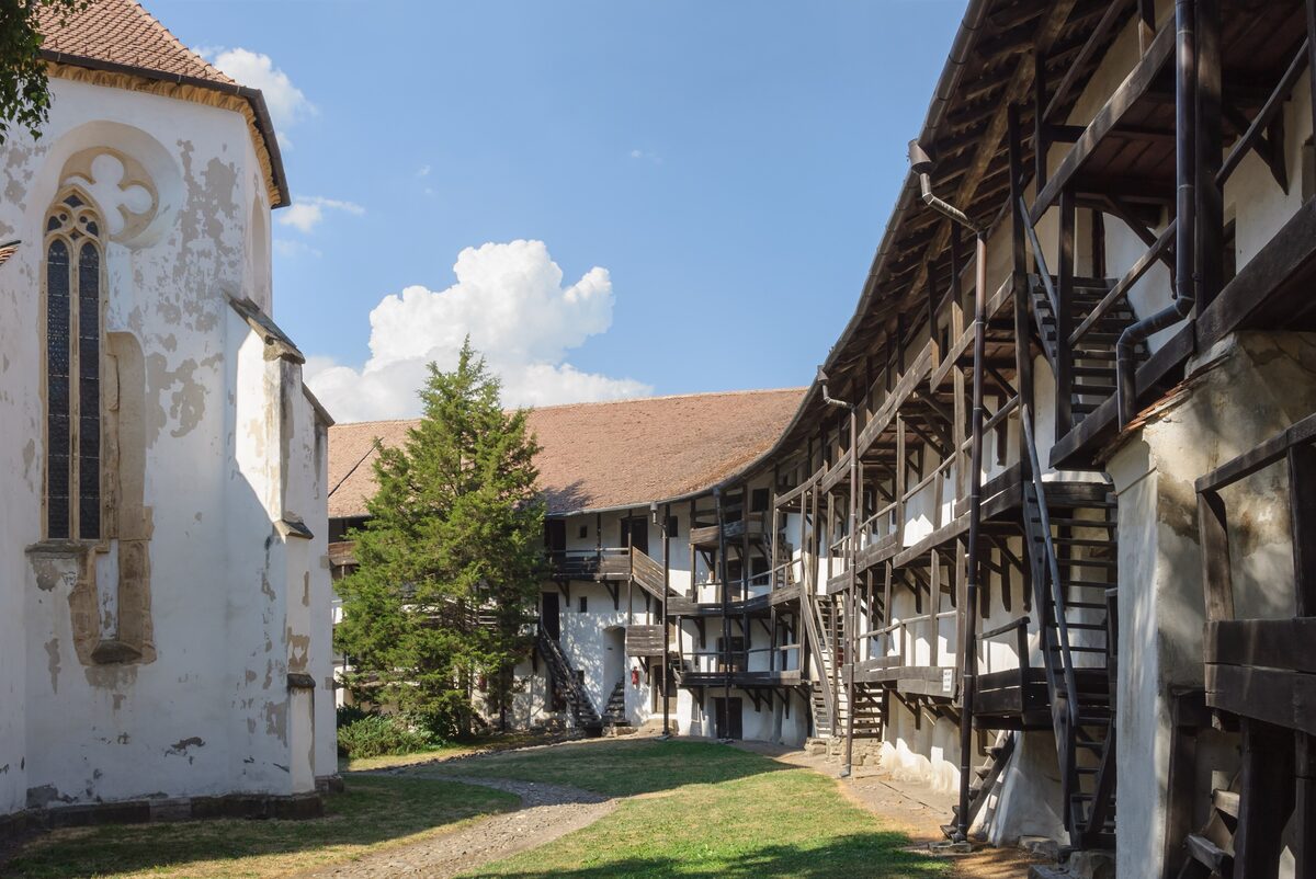 Inside the walls of the fortified church at Prejmer, with the white Gothic church on the left and rows of storage rooms with wooden stairs and galleries along the walls