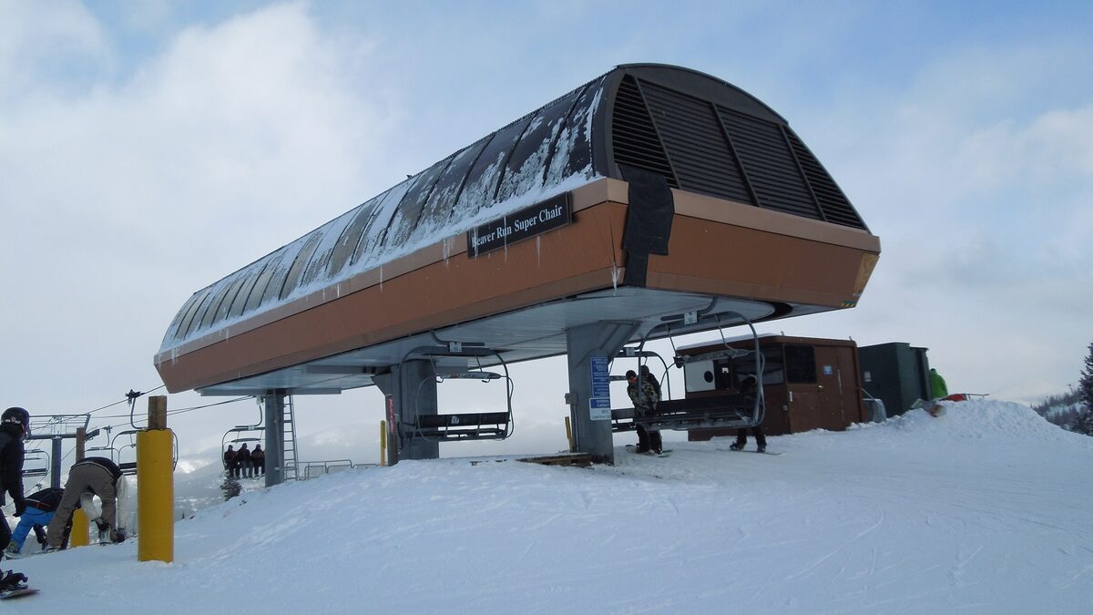 The top terminal of the Beaver Run SuperChair on Peak 9, with snow around the station and skiers beside it