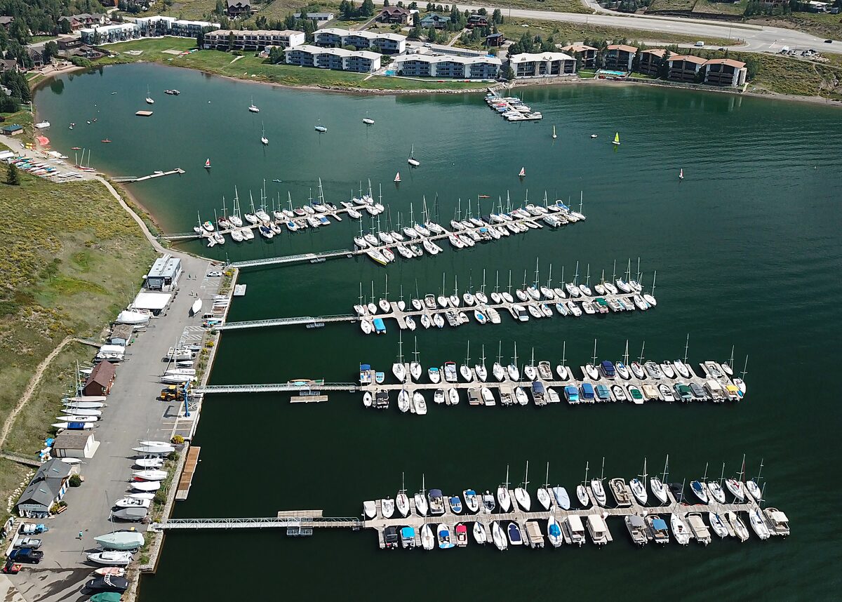An aerial view of the Frisco Bay Marina on Dillon Reservoir, with rows of boats at the docks and the town's buildings along the shore