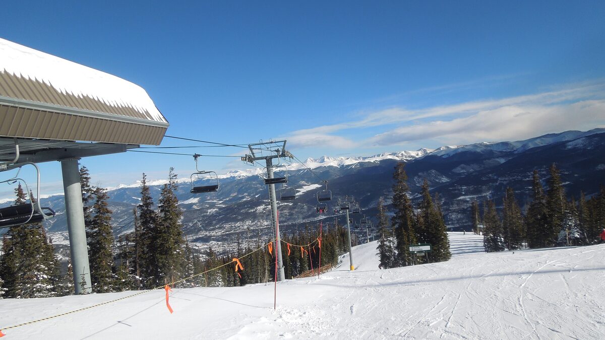The top of the Falcon SuperChair on a sunny morning, with a snow-covered run and the Blue River valley beyond