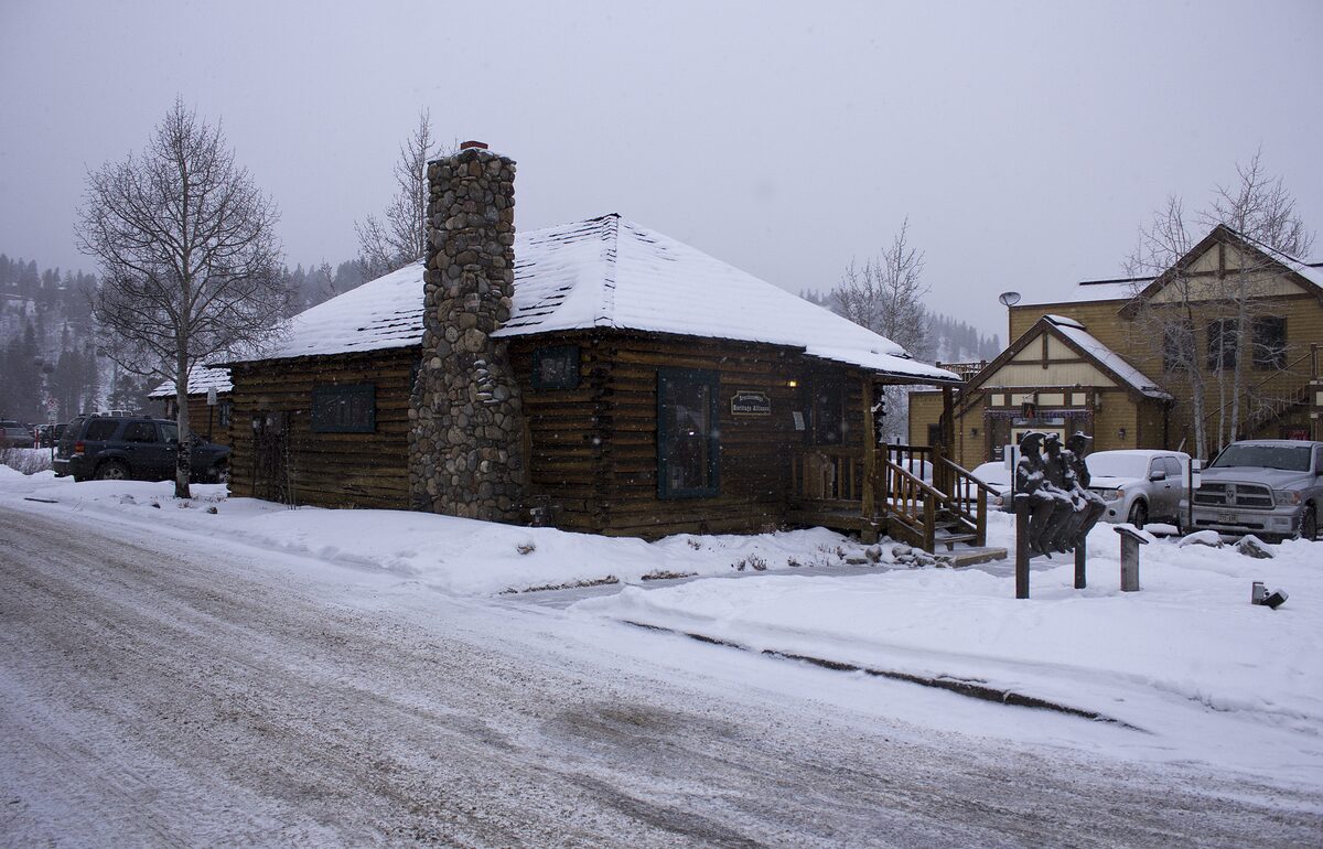 A snowy corner of North Main Street with the log-built Breckenridge Heritage Alliance office, the group that runs the town's history museums