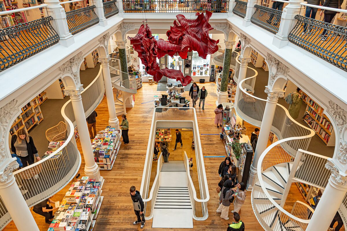 Looking down into Cărturești Carusel: white curving balconies and spiral staircases around a wooden floor with book tables