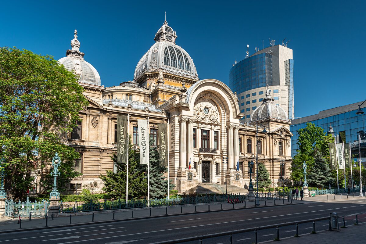 The CEC Palace on Calea Victoriei, with its glass-and-metal central dome and arched entrance, under a clear blue sky