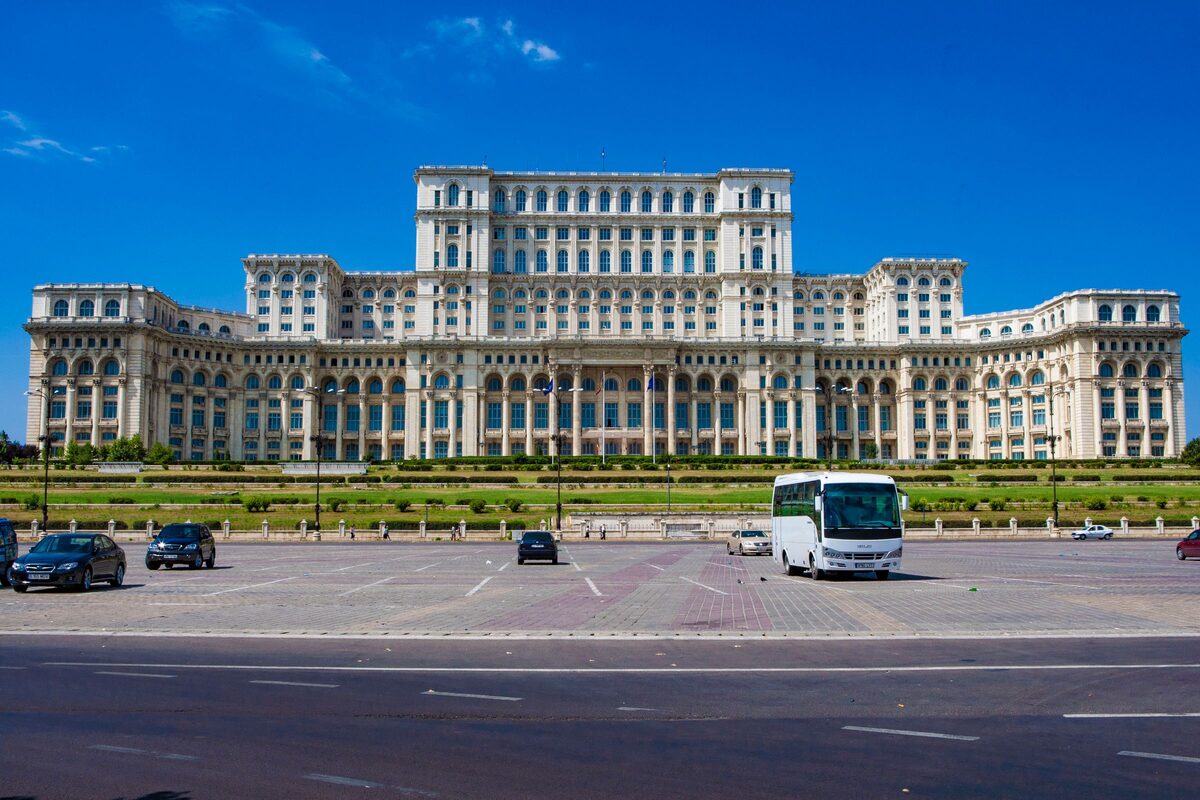 The full front of the Palace of the Parliament under a deep blue sky, seen across the wide empty square in front of it
