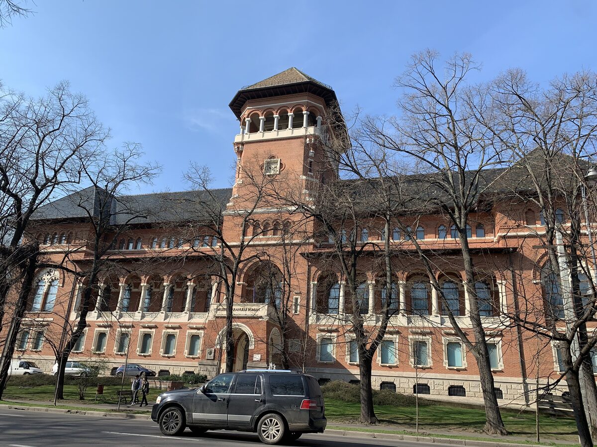 The red-brick neo-Romanian building of the National Museum of the Romanian Peasant, with its arcaded loggia tower, behind bare winter trees