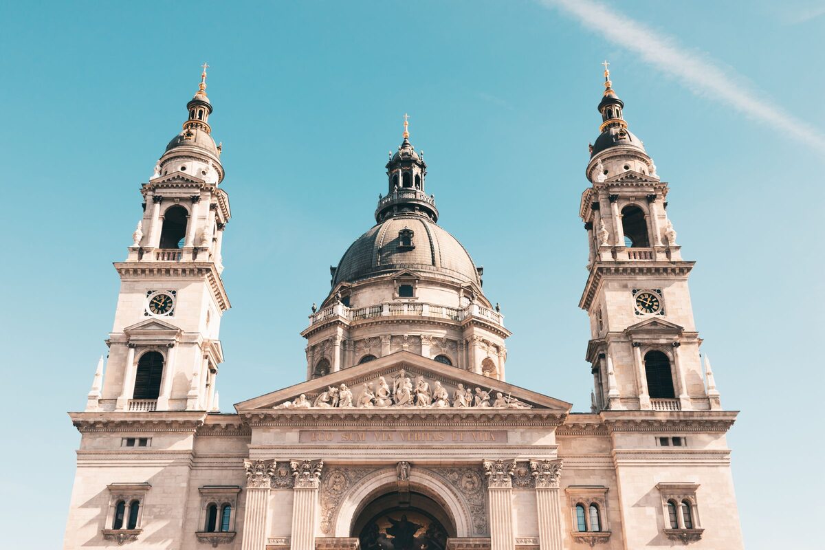 The front of St. Stephen's Basilica with its two bell towers and central dome against a clear blue sky