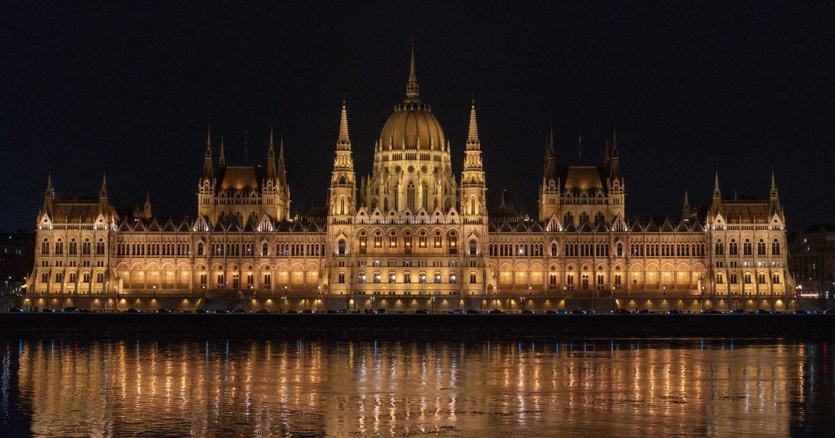The Hungarian Parliament lit up gold at night, its reflection shimmering in the Danube