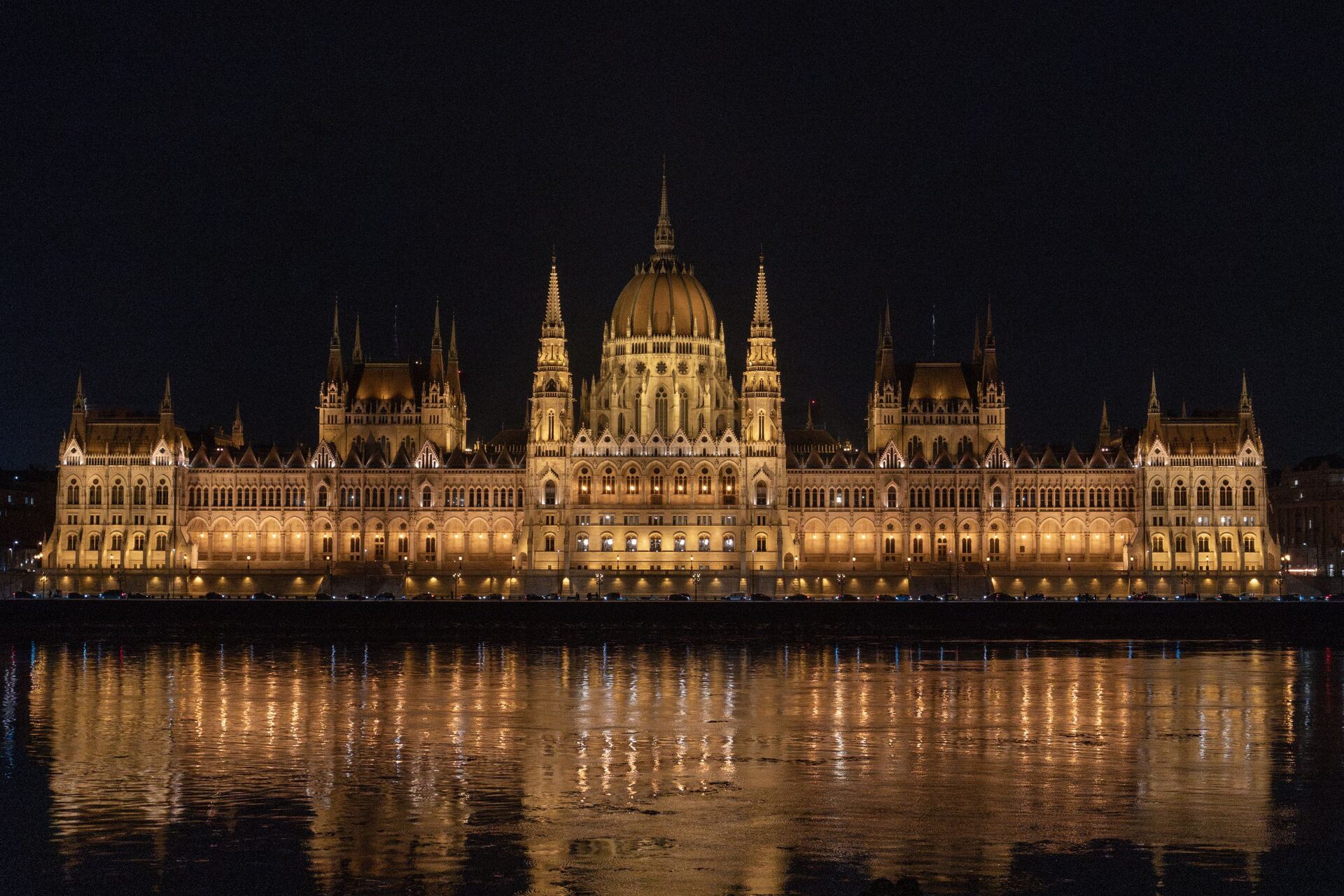 The Hungarian Parliament lit up gold at night, its reflection shimmering in the Danube