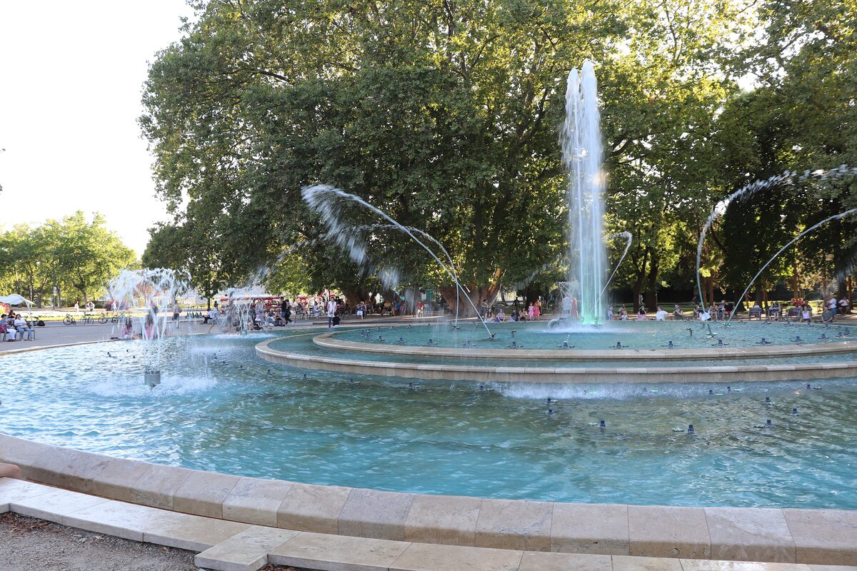 The musical fountain on Margaret Island, with jets of water arcing over a round pool and large shady trees behind