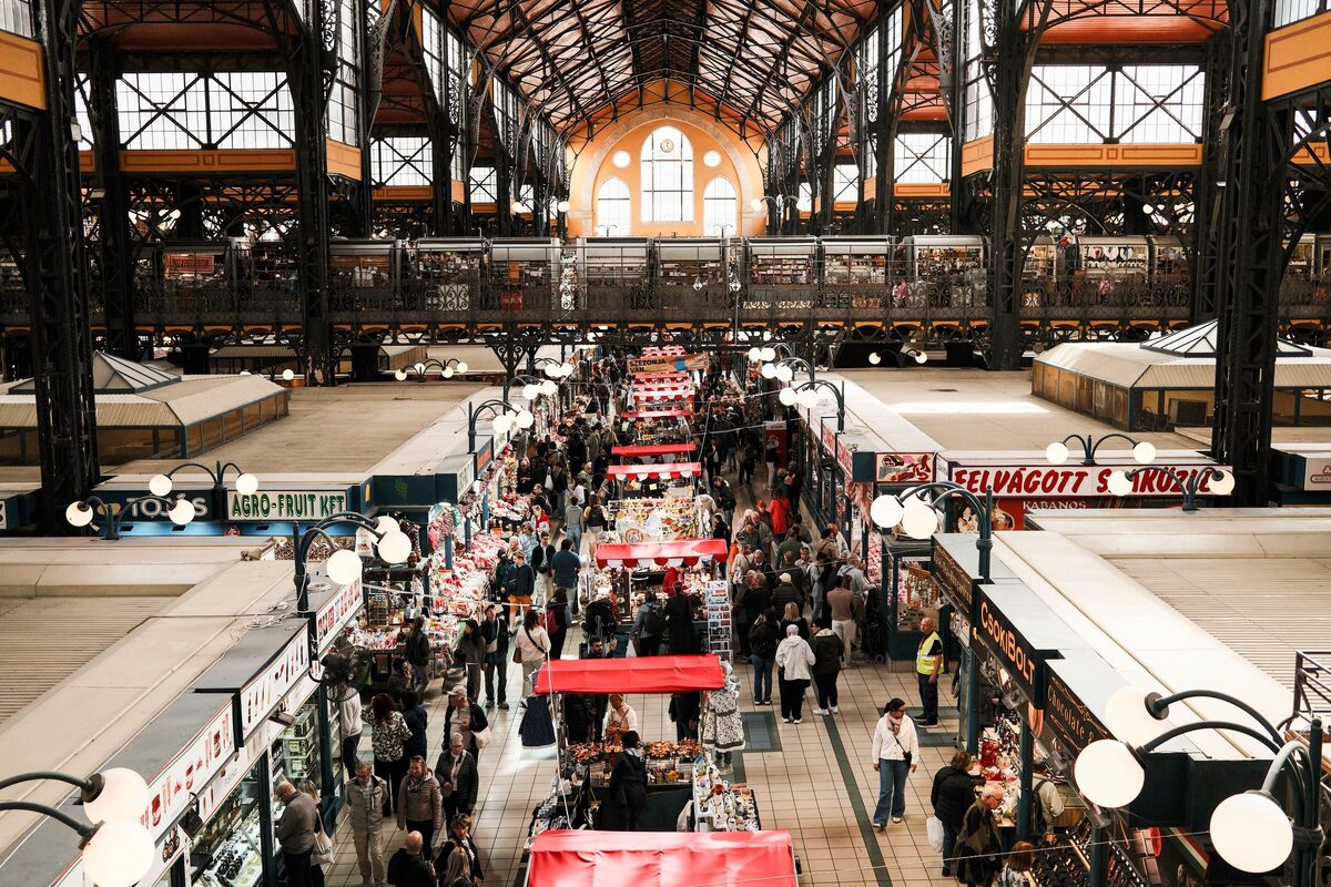 The iron-roofed nave of the Great Market Hall seen from the gallery, with crowds walking between rows of stalls