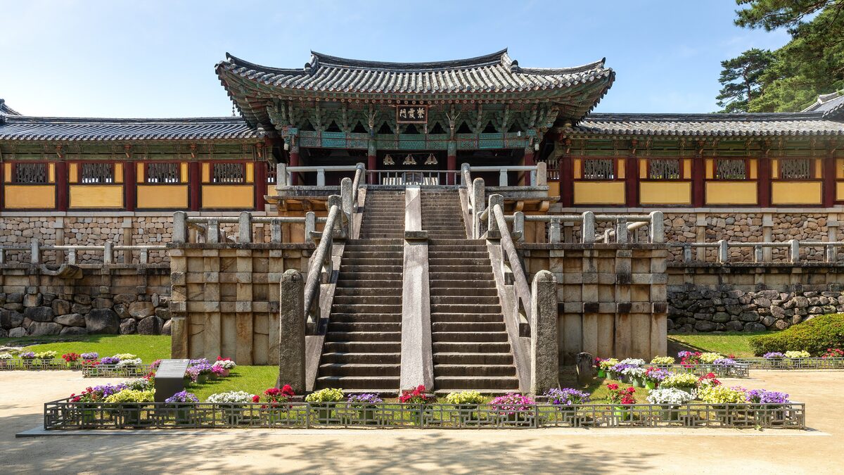 The stone staircase leading up to the wooden halls of Bulguksa temple, with flowerbeds at the gate