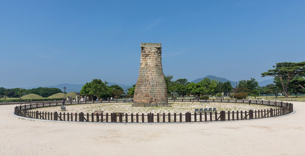 The stone Cheomseongdae observatory inside its fenced lawn under a blue sky