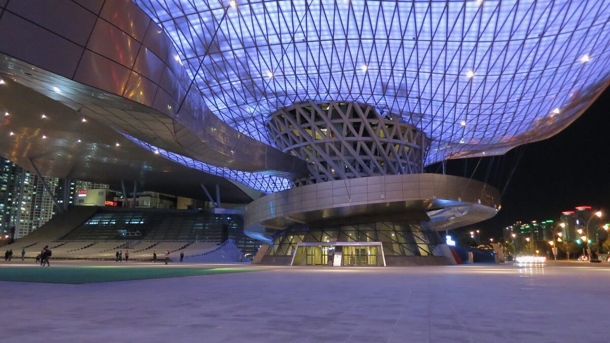 The lattice roof of the Busan Cinema Center, lit in blue and violet above an empty hall