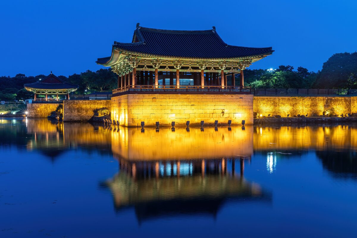 Donggung Palace lit up at blue hour, its reflection hanging in the still water of Wolji Pond