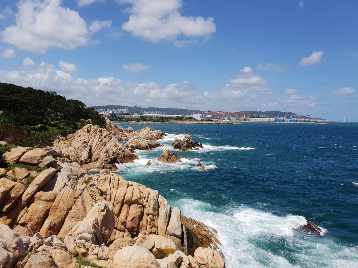 Rugged rock headland at Daewangam Park in Ulsan, with surf breaking on the coast and a blue sky over the sea