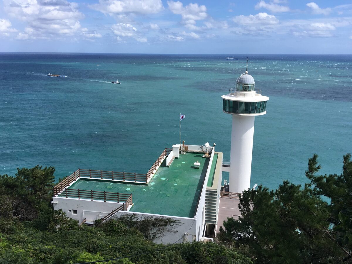 The white Yeongdo Lighthouse on the cape, with its green-floored viewing deck and open sea behind it