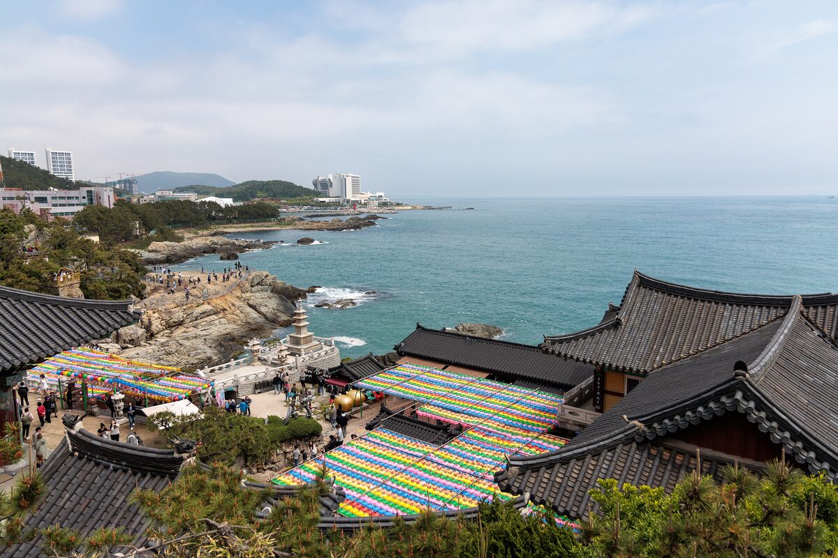 Colored temple flags and the rooftops of Haedong Yonggungsa on the rocks above the sea