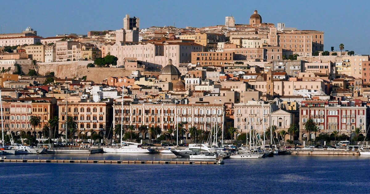 The Castello hill of Cagliari above the marina, with pastel waterfront buildings and the cathedral dome