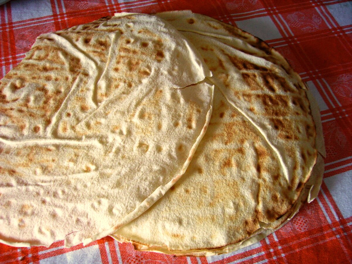 Sheets of crisp pane carasau flatbread stacked on a red checked cloth