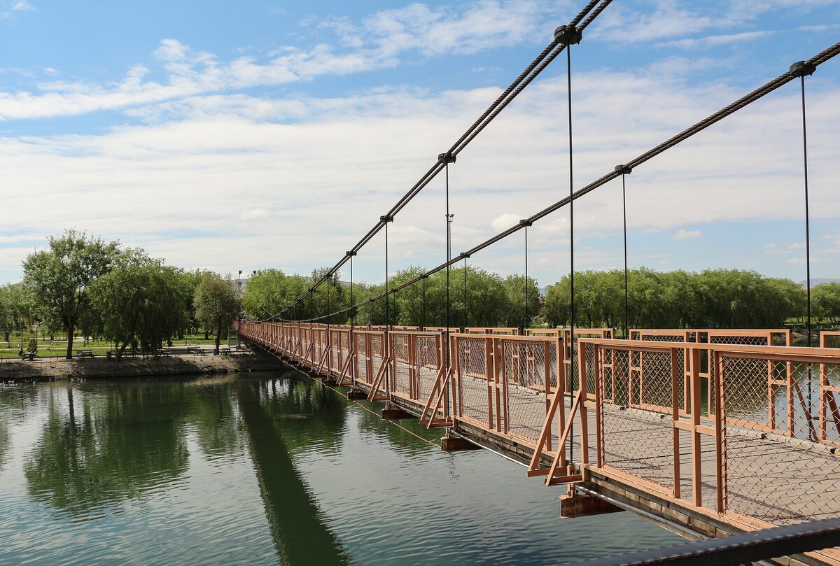 A red suspension footbridge over the green Kızılırmak river in Avanos