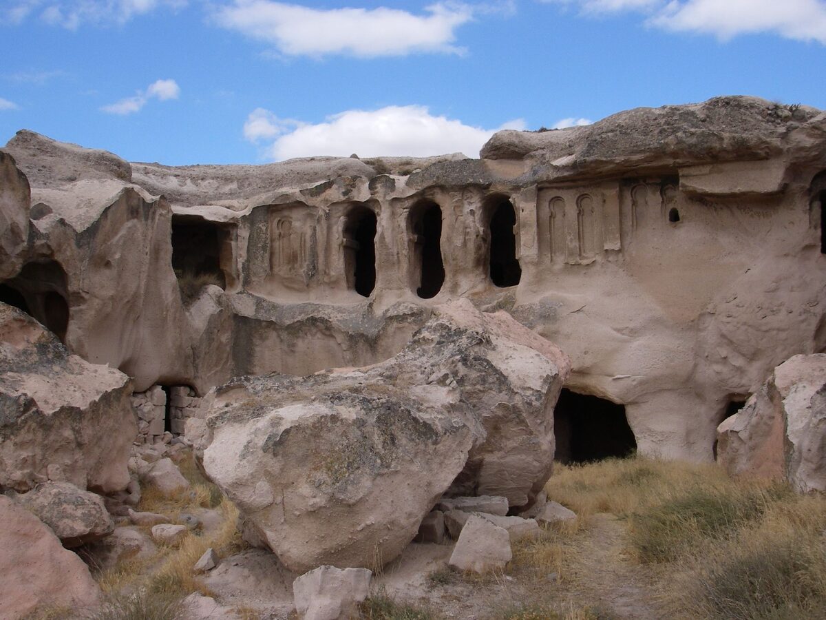 The carved rock facade of Açıksaray near Gülşehir, with a row of arched niches above fallen boulders