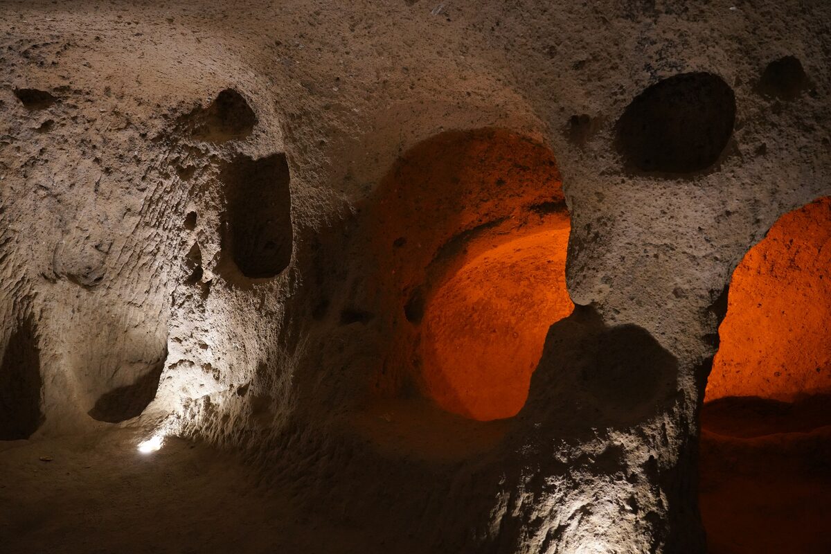 Rough-cut rooms and passages of the Kaymaklı underground city, lit with warm orange lamps