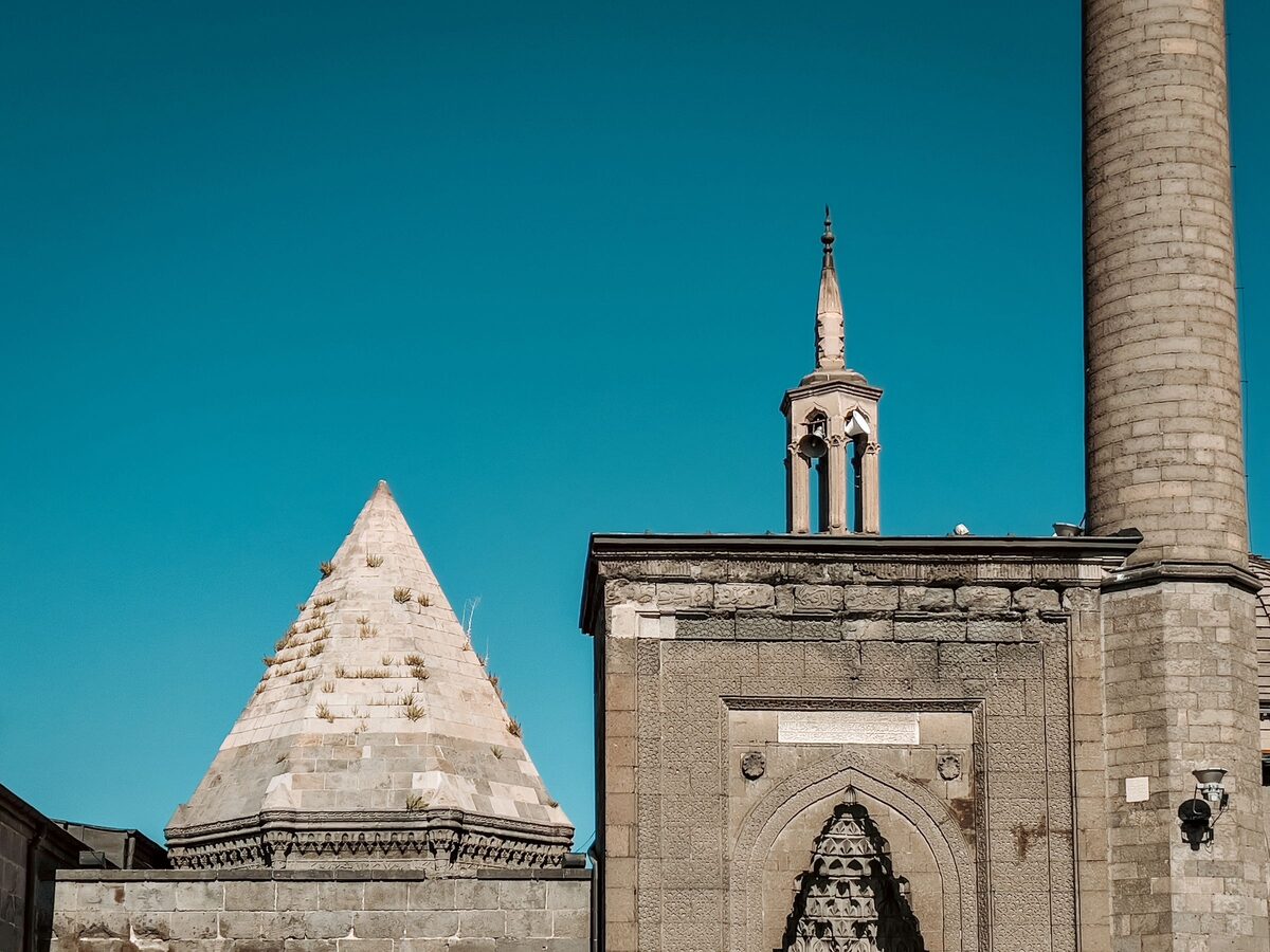 The Seljuk Hunat Hatun complex in Kayseri, with a pyramid-roofed tomb beside a carved stone portal and minaret