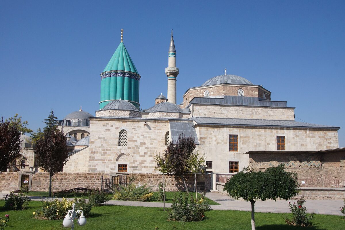 The Mevlana Museum in Konya with its fluted turquoise dome and minaret behind a garden