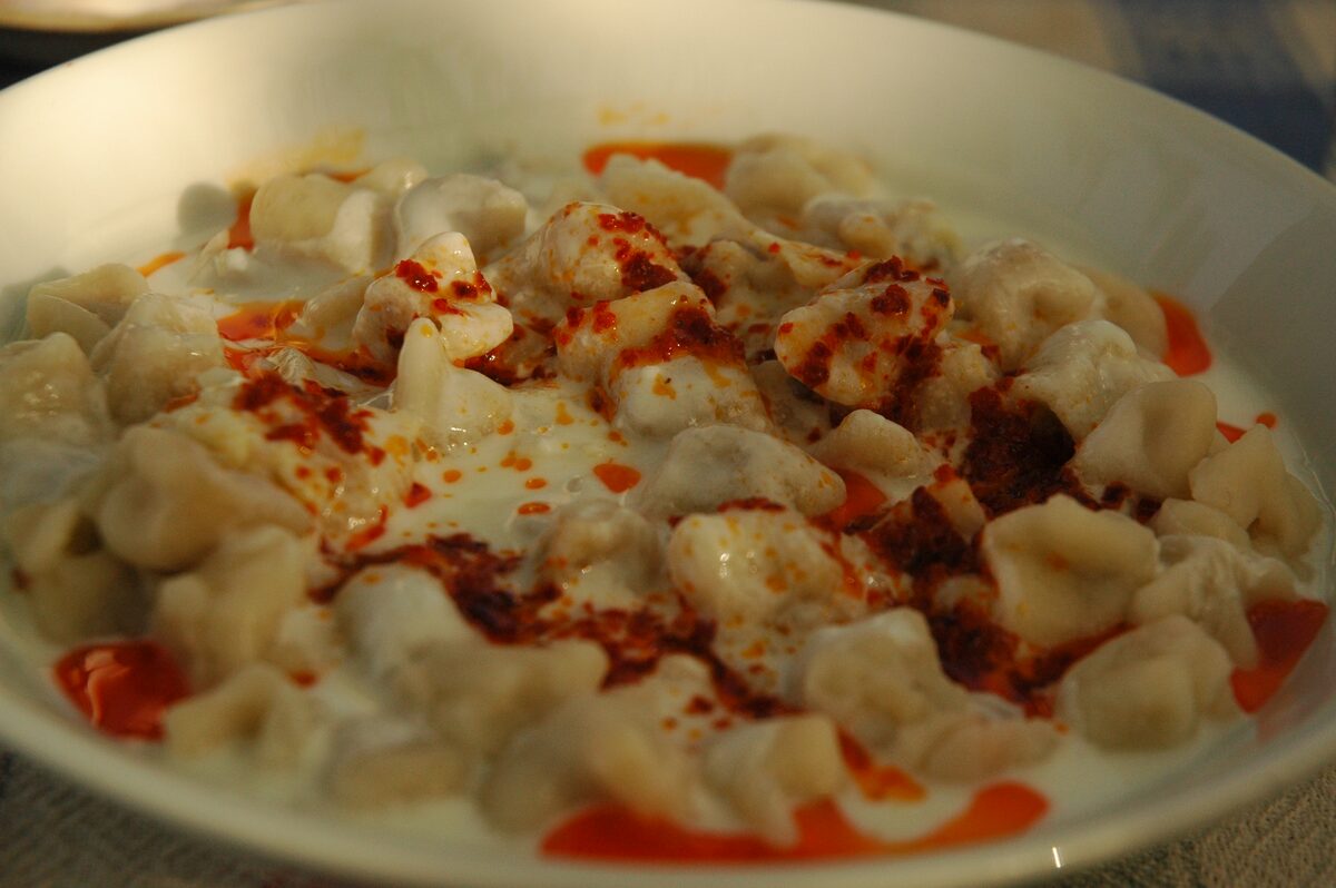 A plate of mantı dumplings under yogurt with red pepper butter, in Cappadocia