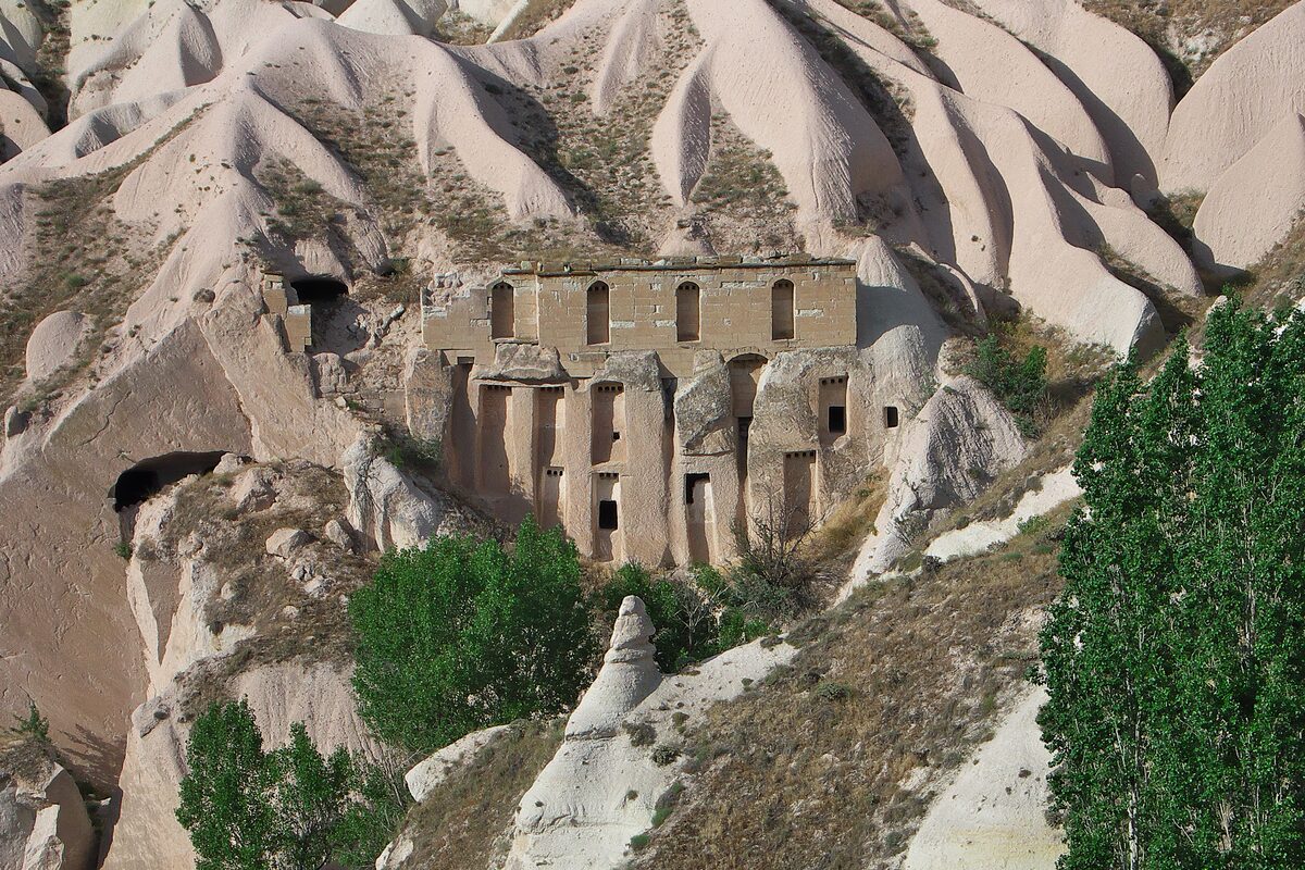 A pigeon house with rows of small arched openings carved into a pale cliff in Pigeon Valley