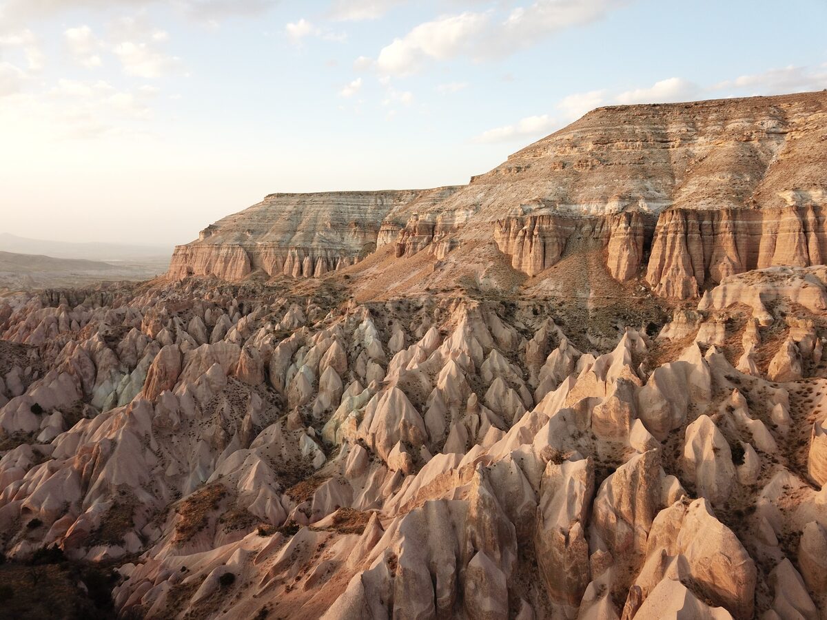 Pink and cream ridges of the Red and Rose valleys under a flat-topped mesa in warm late-afternoon light
