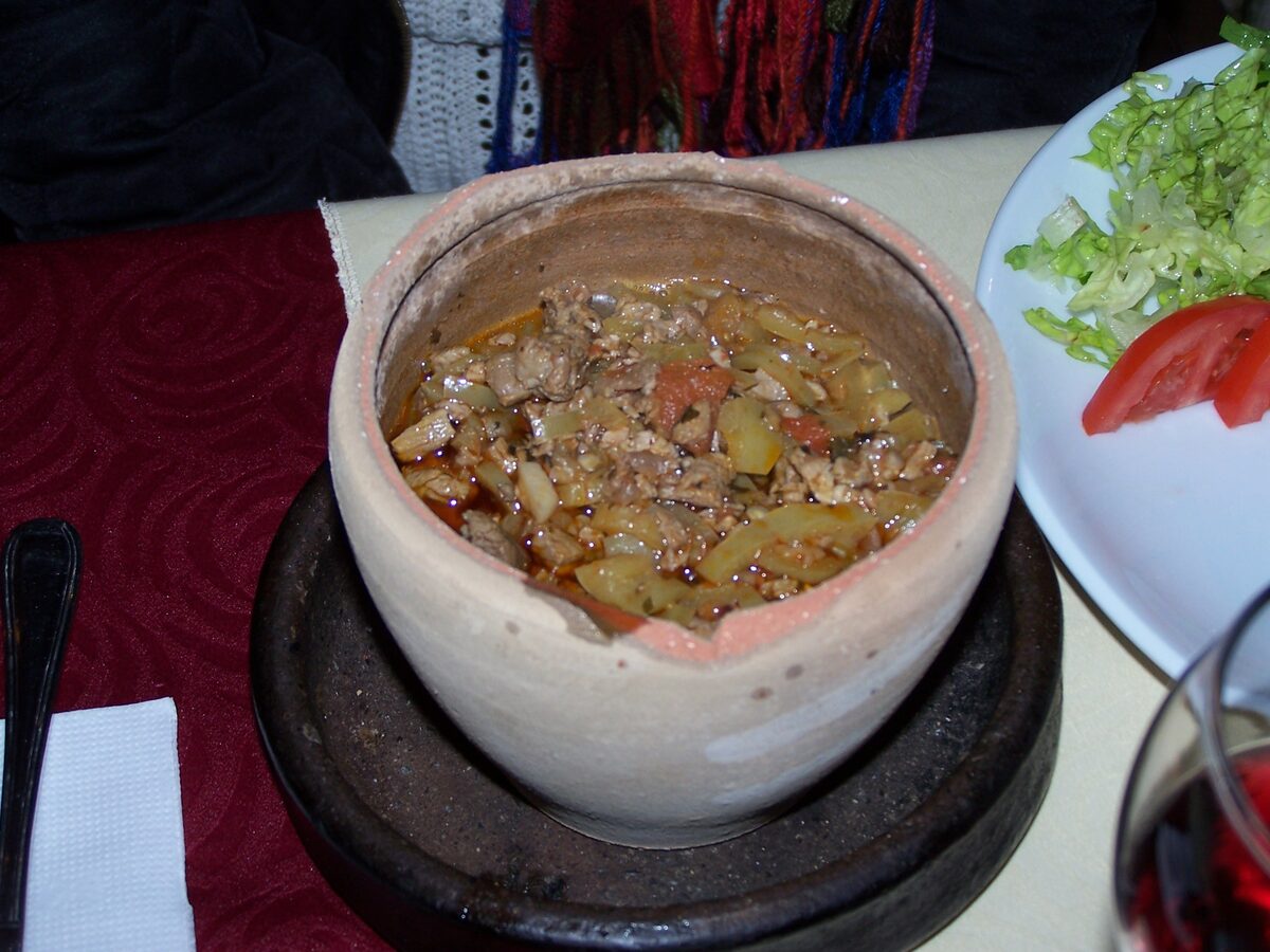 An opened clay pot of testi kebab, full of stewed meat and vegetables, on a restaurant table in Göreme