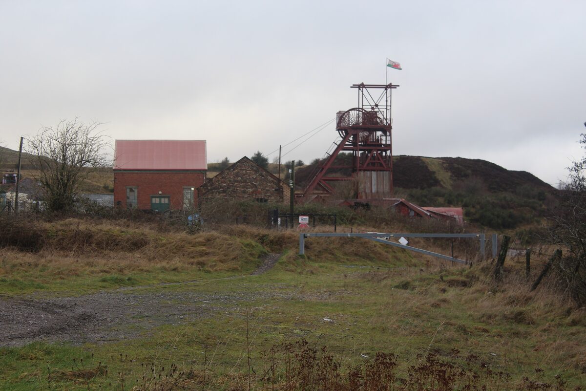 The pithead winding gear and red brick buildings of Big Pit, the old coal mine at Blaenavon, on a hillside