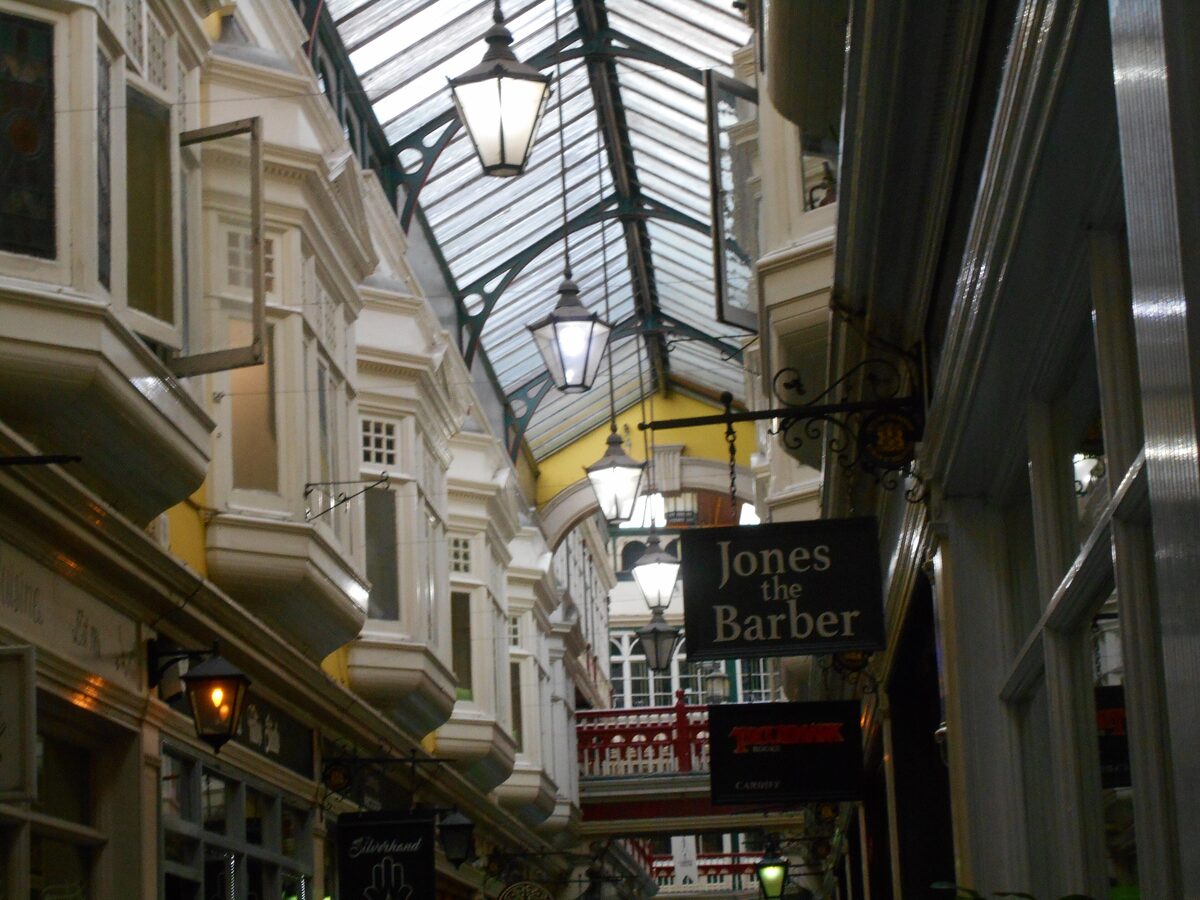 Inside Castle Arcade in Cardiff, a Victorian shopping arcade with a glass roof, hanging lamps and wooden shopfronts on two levels