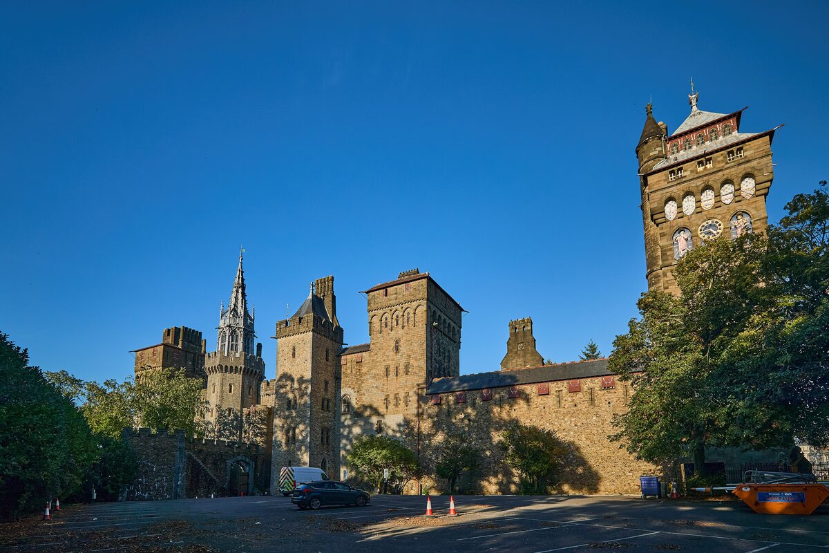 Cardiff Castle, with Victorian Gothic towers and a tall clock tower rising behind the old walls under a blue sky