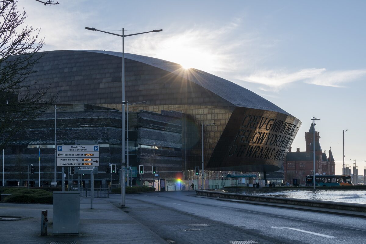 The curved bronze-colored steel roof of the Wales Millennium Centre with its huge cut-out letters, glinting in low sun