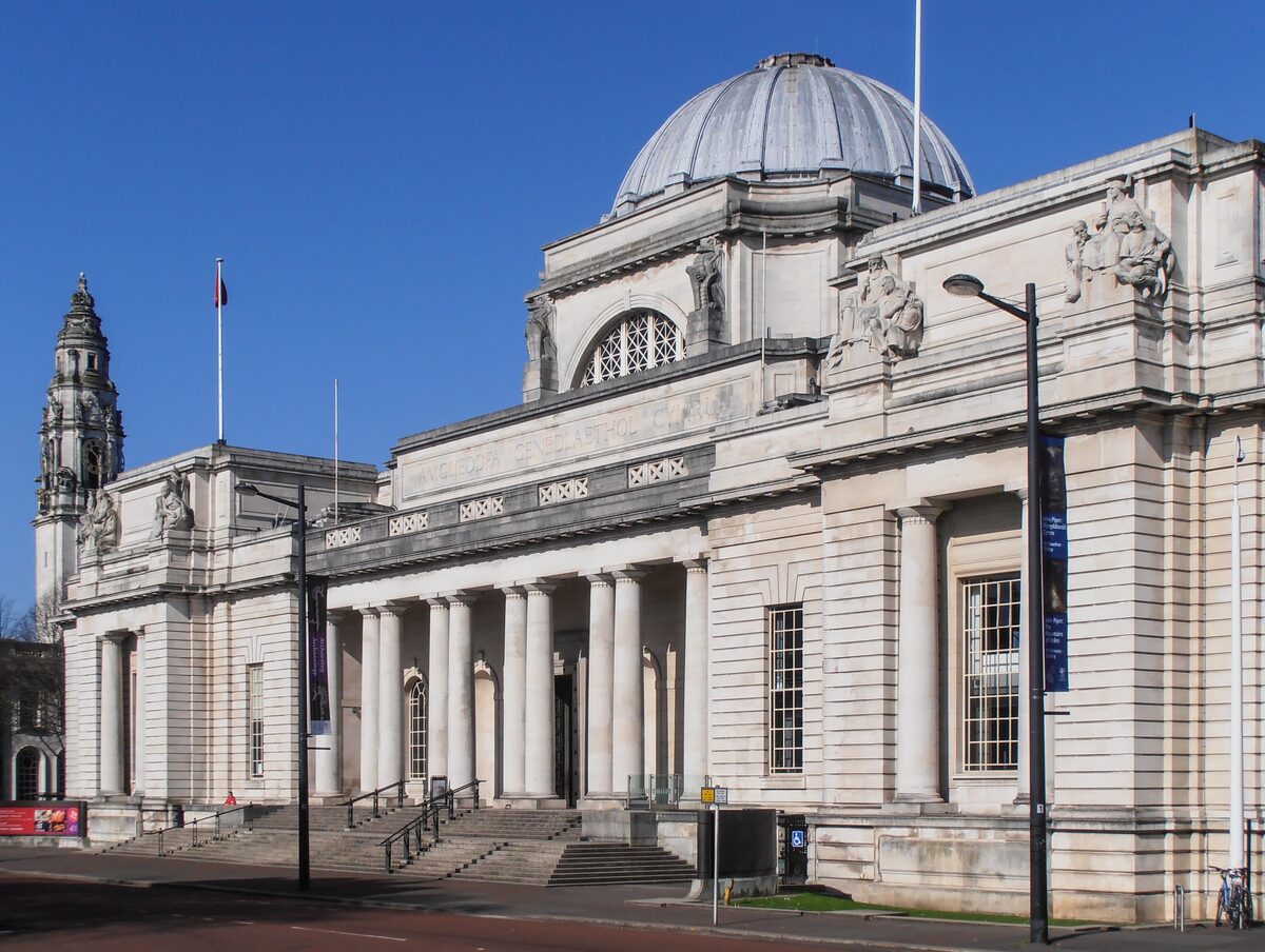The white Portland stone front of National Museum Cardiff with its columns and dome, under a blue sky