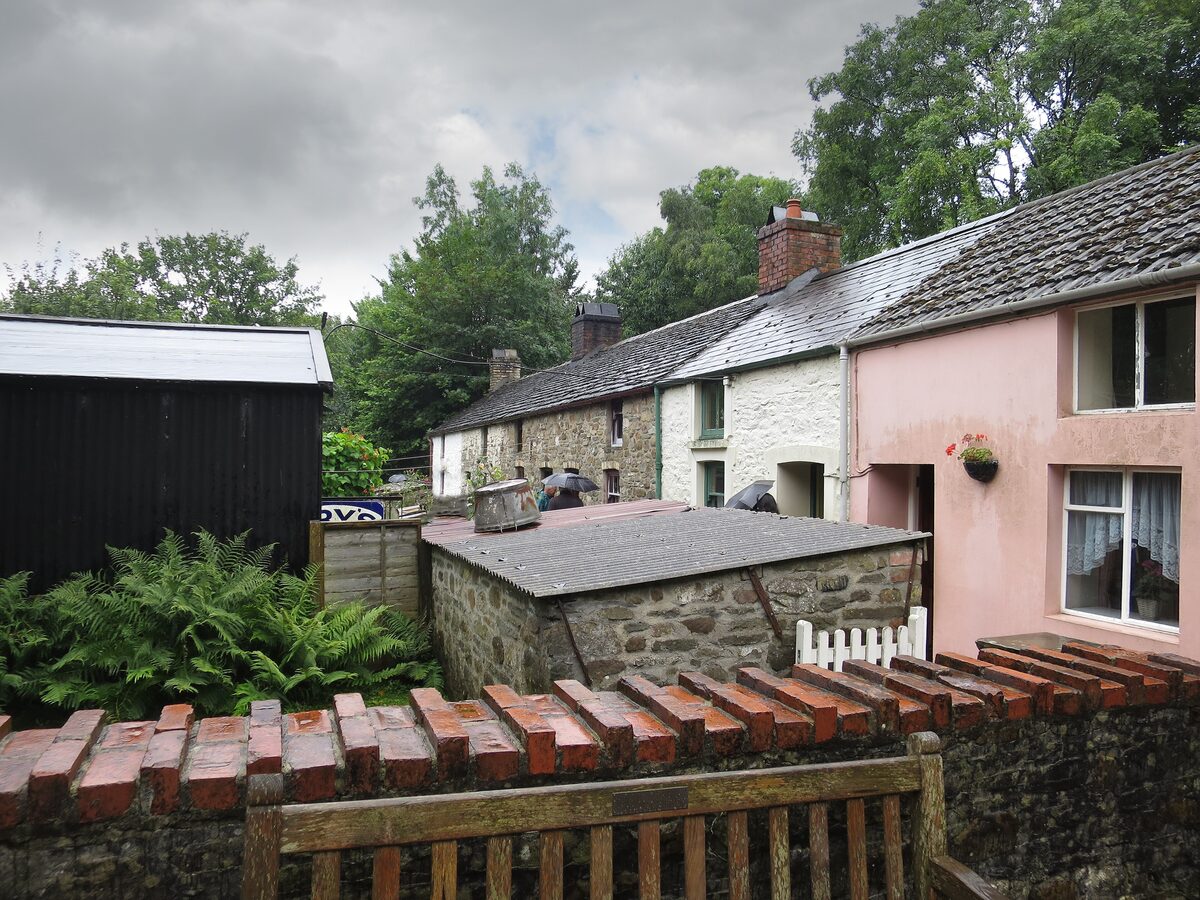 A row of ironworkers' cottages at St Fagans, painted in different colors, with small gardens in front