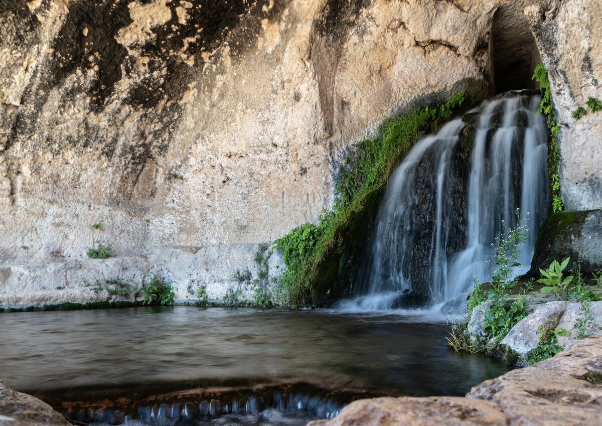 Waterfall over the limestone rock of the Nymphaeum in the Neapolis park in Syracuse, falling into a pool
