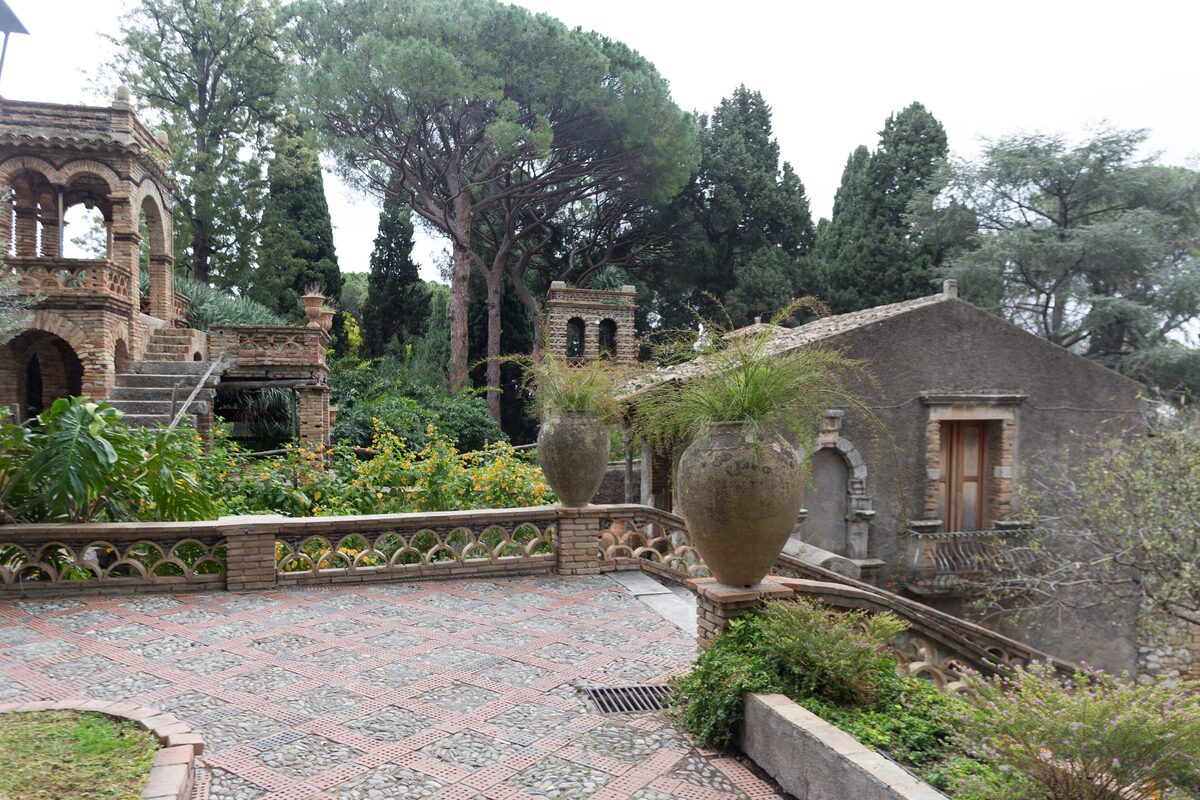 A mosaic terrace and stone follies among pines in the Villa Comunale gardens of Taormina